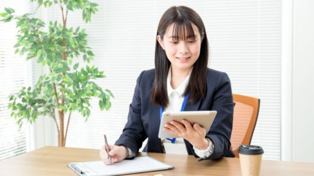 タブレットを使い探し物をするスーツ姿の若い女性