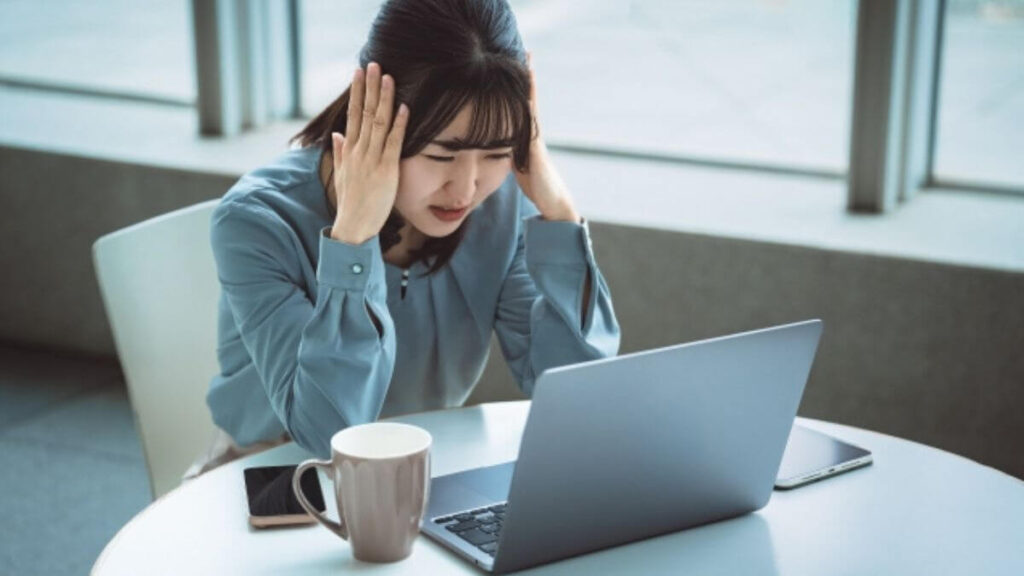パソコン前で頭を抱え悩む若い女性