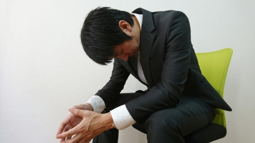椅子に座りながら落ち込むスーツ姿の男性