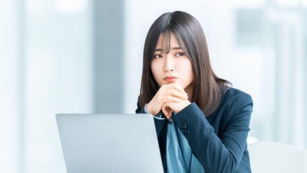 パソコンの前で悩んでいる表情をするスーツ姿の女性