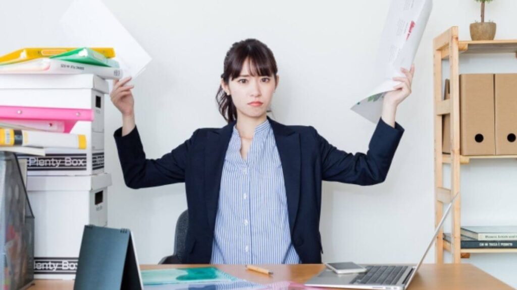 自宅で書類やパソコンに囲まれるスーツ姿の女性