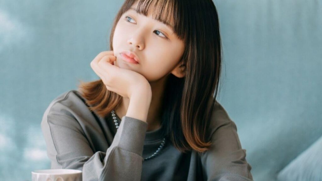 机に肘を置き悩む若い女性