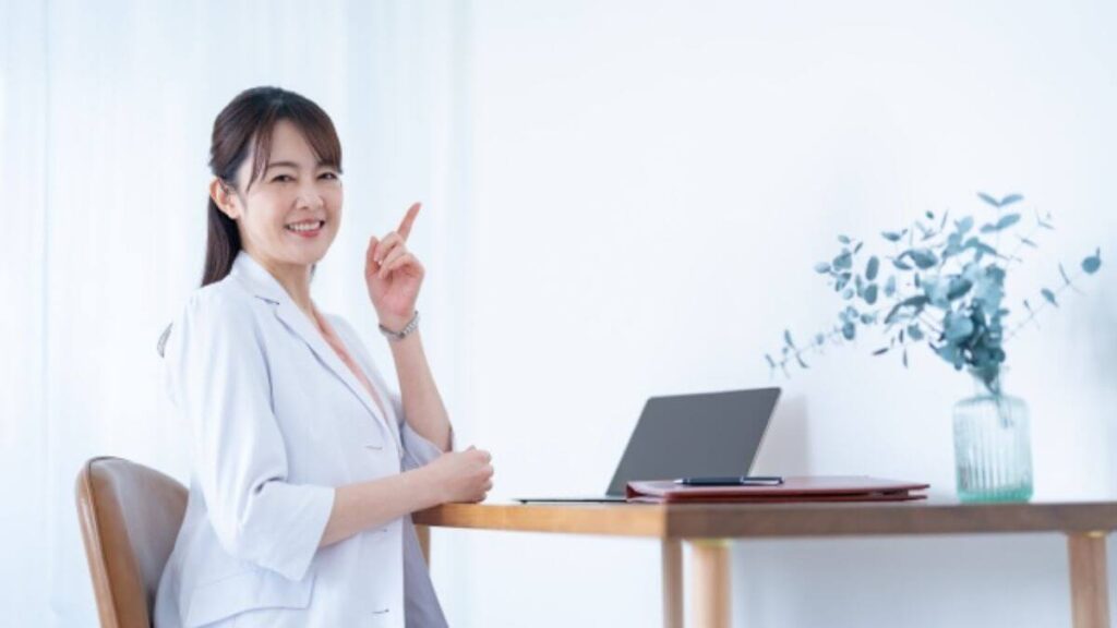 指をあげ笑顔で微笑む白衣姿の女性カウンセラー