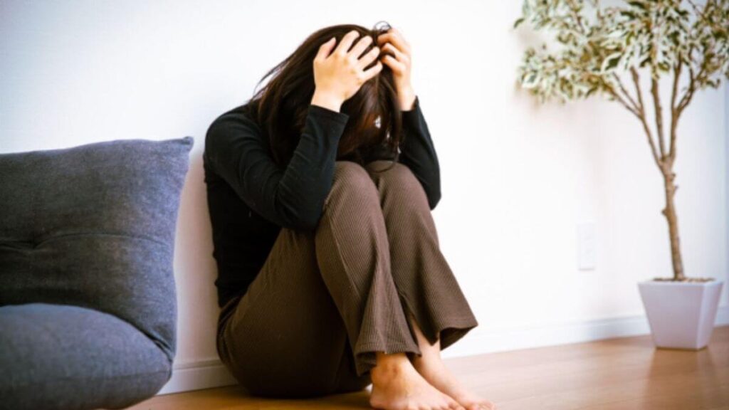 部屋でうずくまって落ち込む若い女性