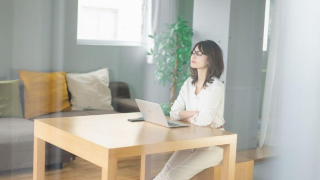 パソコンの前で目をつぶり後悔する女性