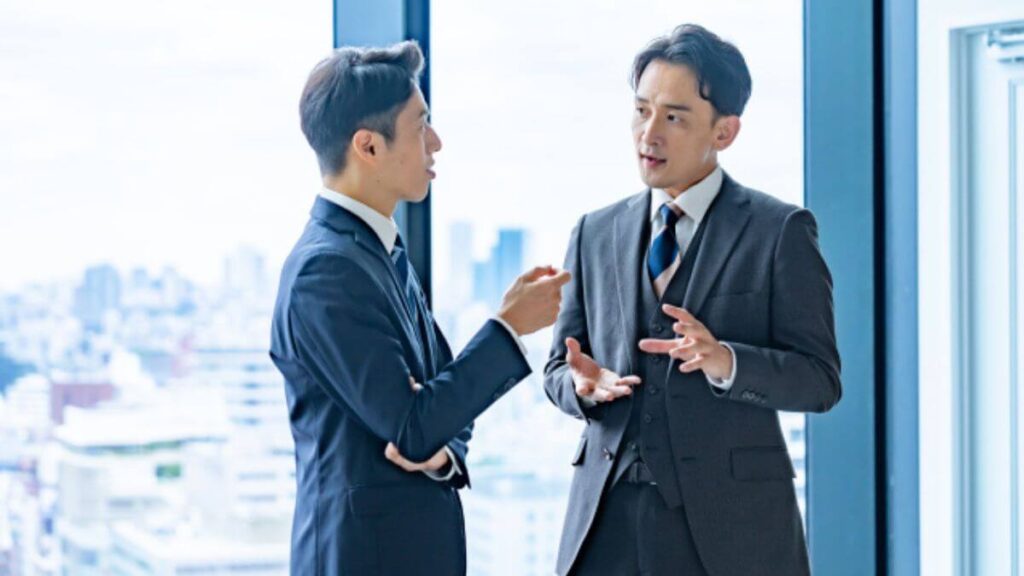 上司に説明をするスーツ姿の若い男性