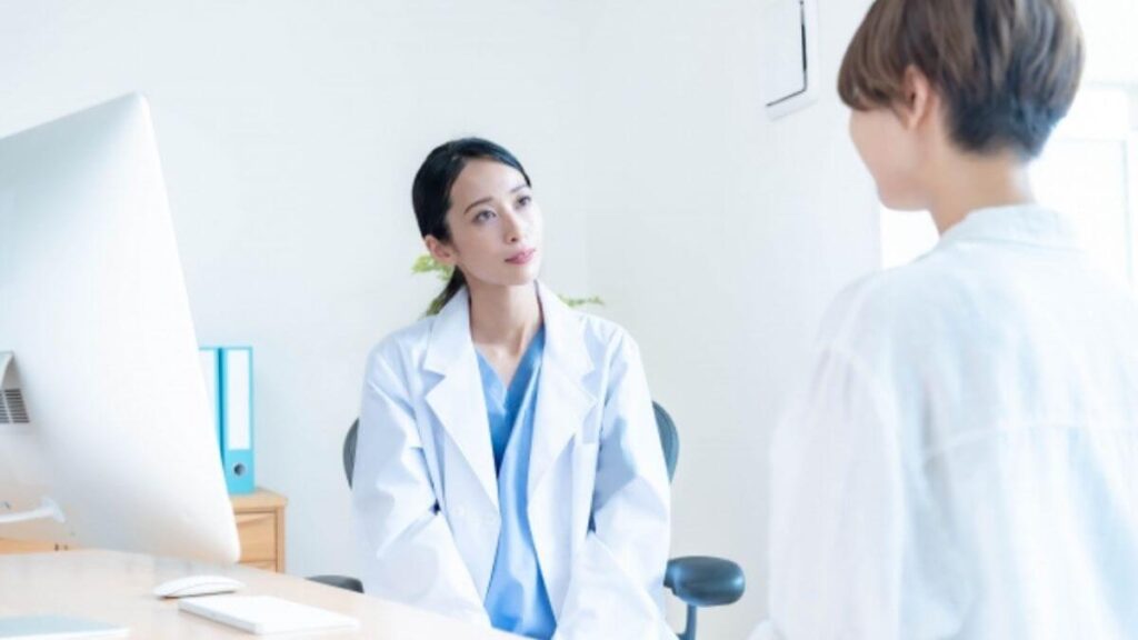 相談者の話を真剣に聞く白衣姿の女性カウンセラー